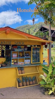 a small yellow shack with pineapples on the outside and an orange awning