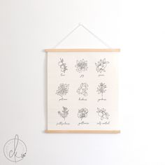 a white wall hanging on the side of a wall next to a wooden frame with flowers drawn on it