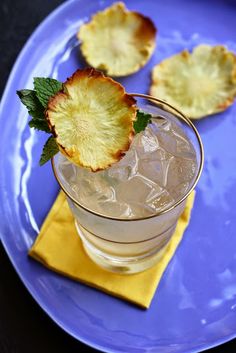 a blue plate topped with two glasses filled with ice and pineapple slices on top of it