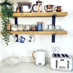 two wooden shelves with coffee mugs and toaster on them in the corner of a kitchen