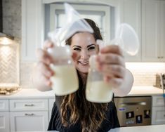 a woman holding up two glasses filled with liquid