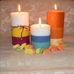 three candles sitting next to each other with candy in front of them on a table