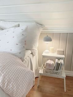 a bed with white sheets and pillows on top of it next to a night stand