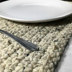 a white plate sitting on top of a crocheted table cloth next to a fork