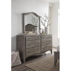 a bedroom with a dresser, mirror and vases on the floor in front of it