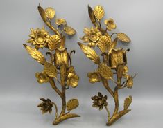 two golden metal flowers and leaves on a gray background