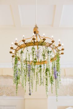 a chandelier with flowers hanging from it's sides in a room filled with windows