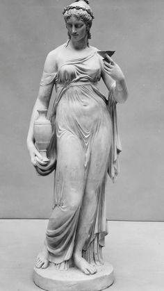 an antique statue of a woman holding a vase