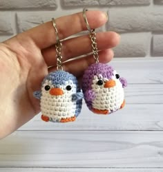 two small crocheted birds are being held by someone's hand