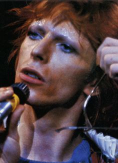 a woman with red hair holding a microphone in her right hand and looking off to the side