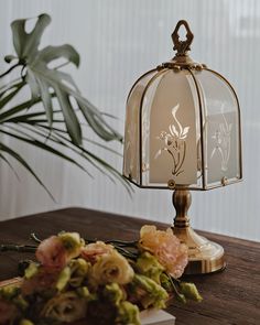 a lamp that is sitting on top of a table next to some flowers and a potted plant