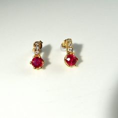 Here we have a gorgeous pair of natural earth mined vivid red ruby and sparkly diamond accent earrings crafted in solid 14K yellow gold. Together the pair weigh 3.2 grams approximately making them ideal for everyday wear. Each pretty earring measures approximately 1/2" long by 1/4" wide (12.6mm x 6.4mm). They are in lovely condition and are ready to gift or to wear. Each ruby measures respectively 5.14mm x 2.70mm and 5.08mm x 3.84mm. They weigh 0.52 carats and 0.84 carats. The diamond accents ea Luxury Red Ruby Earrings, Luxury Red Brilliant Cut Earrings, Brilliant Cut Ruby Round Earrings, Ruby Gemstone Earrings Round Cut, Formal Red Diamond Earrings With Brilliant Cut, Formal Round Cut Ruby Earrings, Ruby Earrings With Prong Setting In Round Cut, Ruby Earrings With Round Cut And Prong Setting, Ruby Earrings With Prong Setting And Round Cut