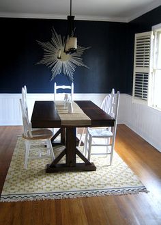 a dining room table with chairs and a rug on the floor in front of it