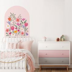 a pink and white bedroom with flowers painted on the wall above the bed, along with two nightstands