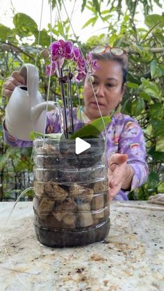 a woman pouring water into a jar filled with rocks