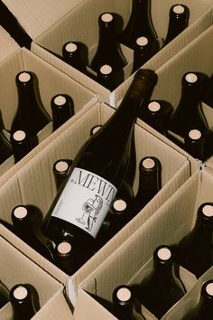 a bottle of wine sitting inside of a cardboard box filled with black and white bottles