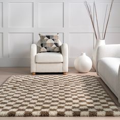 a living room with a white chair and brown rug on the floor next to two vases