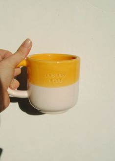 a hand holding a yellow and white coffee cup