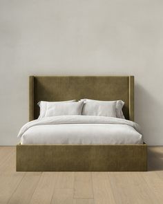 a bed with white linens and pillows in a minimalistic bedroom setting on hardwood flooring