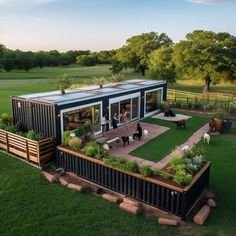 an aerial view of a house made out of shipping containers with people and dogs in the yard