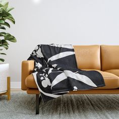 a couch with a black and white blanket on top of it next to a potted plant