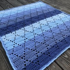 a blue and white crocheted blanket sitting on top of a wooden floor