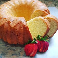 a bundt cake with one slice cut out and two strawberries on the side