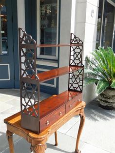 a wooden bench sitting on top of a sidewalk next to a potted green plant