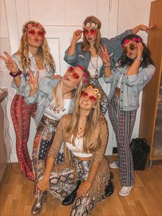 four girls in hippie outfits posing for the camera with their hands up and one girl wearing red sunglasses