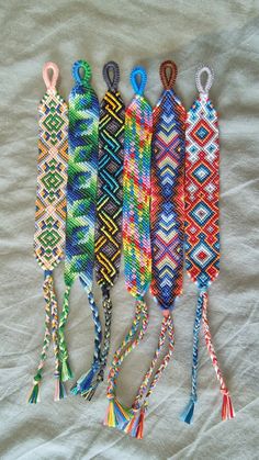 five different colored bracelets are lined up on a bed