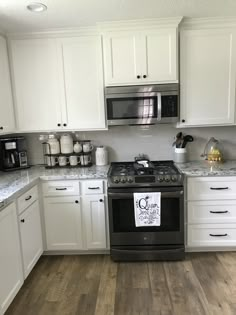 a kitchen with white cabinets and stainless steel stove top oven in the middle of it