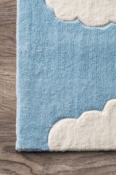 a blue rug with white clouds on the top and bottom, sitting on a wooden floor