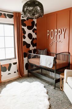 a baby's room with an animal print wallpaper and black metal crib