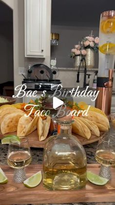 a wooden table topped with glasses and bottles filled with liquid next to sliced limes