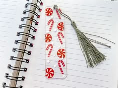 an open notebook with candy canes and tassel on it next to a notepad