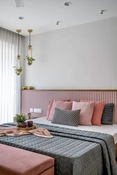 a bed with pink and grey pillows on top of it