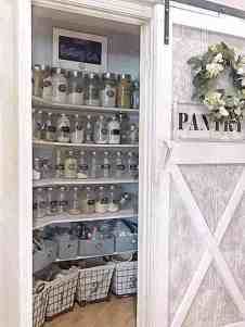 an open pantry door with jars and baskets in the bottom shelf, along with other items