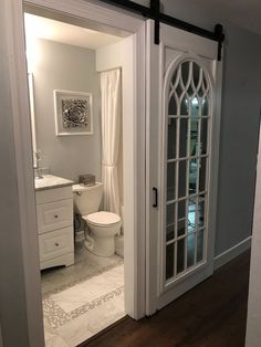 an open door leading to a bathroom with a toilet and sink in the room next to it