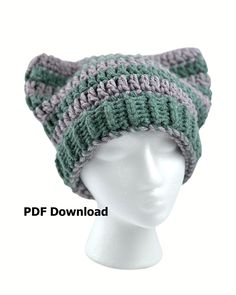 a white mannequin head wearing a green and gray knitted hat with ears