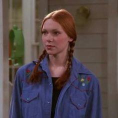 a woman with long red hair wearing a blue shirt and braid in front of her face