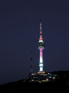 a very tall building lit up in the night sky with lights on it's side