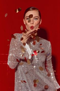 a woman with her hands on her face and confetti falling from her mouth