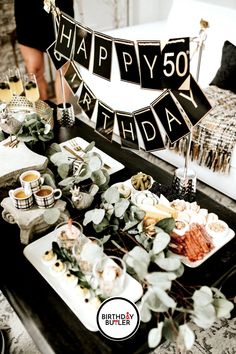 a table topped with plates and cups filled with food next to a sign that says happy 50th