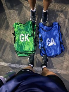 two people standing next to each other with bags on the ground and their feet in the air