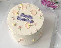 a white birthday cake with pink and purple frosting