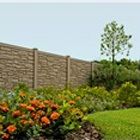 a garden with flowers and grass next to a fenced in area that has a brick wall