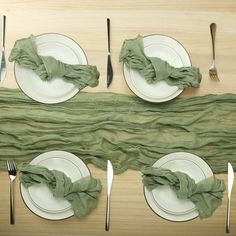 the table is set with plates, silverware and green napkins on top of it