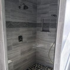 a walk in shower sitting next to a tiled floor and white walls with black accents