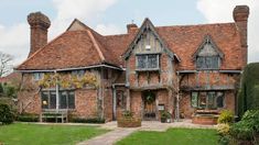 an old brick house with ivy growing on it's roof and windows in the front yard