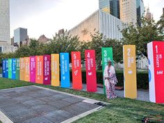 a woman standing in front of colorful banners on the side of a road with buildings in the background